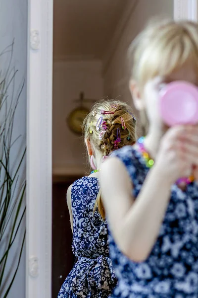 Niña mirándose en el espejo en casa usando una falda y un collar —  Fotos de Stock