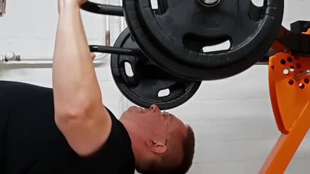 Middle-aged man lying on bench and doing chest press in his homw gym — Stock Video