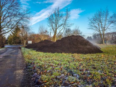 Steaming pile of manure on farm field in the winter clipart