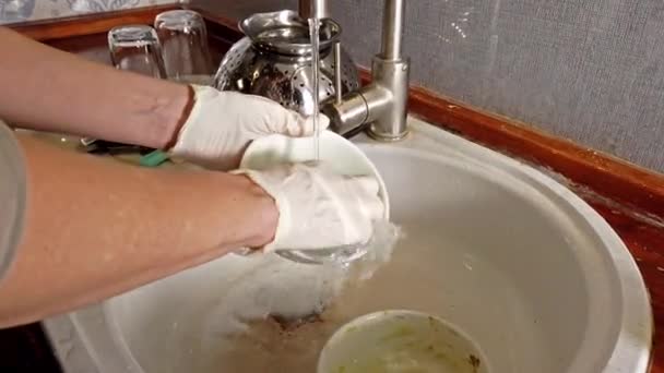 Женщина моет посуду на кухне в перчатках — стоковое видео