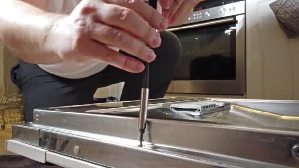 Мужчина-техник чинит посудомоечную машину на кухне — стоковое видео