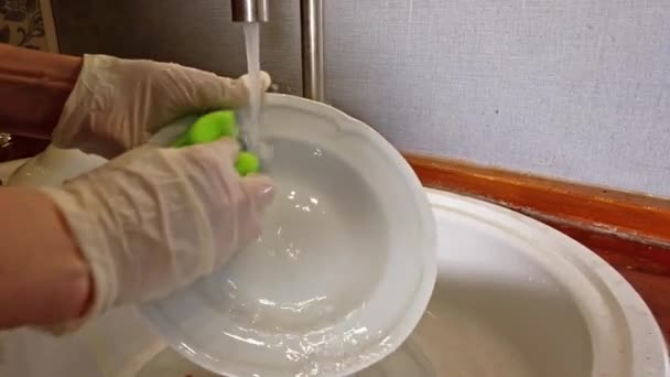 Vrouw wassen plaat in de keuken met handschoenen — Stockvideo