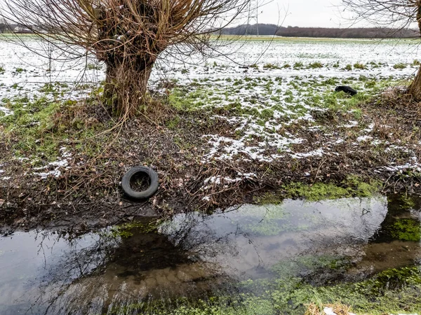 Концепция загрязнения окружающей среды, выбрасывая старые шины в реку — стоковое фото