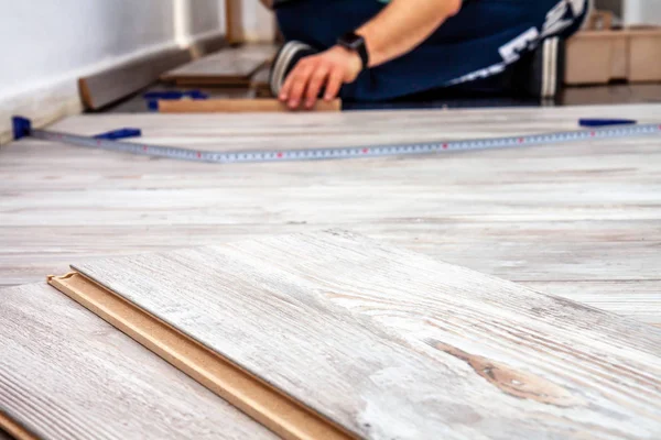 Homem instalando novo piso laminado de madeira em casa . — Fotografia de Stock