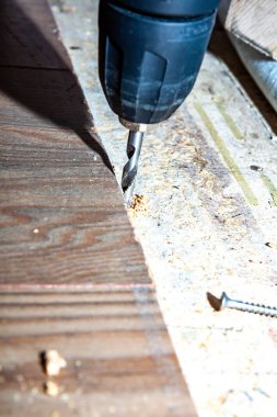 Evde yeni Ahşap laminat yüklerken matkap makinesi kullanan adam.