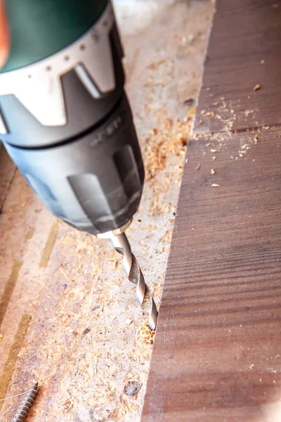 Man using drill machine while installing new wooden laminate flooring at home.