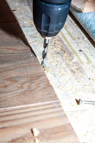 Homem usando máquina de broca durante a instalação de novo piso laminado de madeira em casa . — Fotografia de Stock