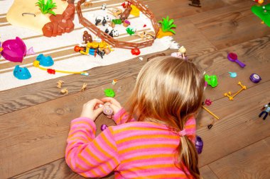 Renkli plastik oyuncak bir sürü ile kapalı ahşap zemin üzerinde oynayan küçük kız çocuk