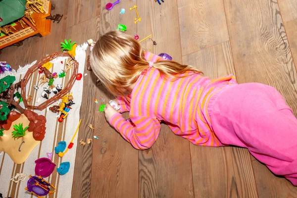 Renkli plastik oyuncak bir sürü ile kapalı ahşap zemin üzerinde oynayan küçük kız çocuk