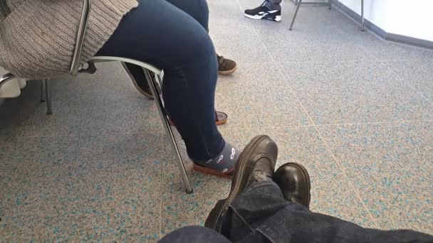 Feet of different people sitting in a waiting room — Stock Video