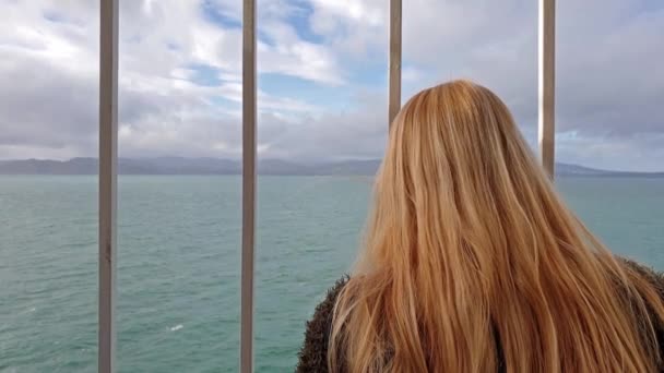 Rubia dama sosteniendo los bares y mirando al mar y la tierra — Vídeos de Stock