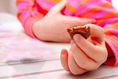 Küçük kız yemek Snickers çikolata bar kahvaltı