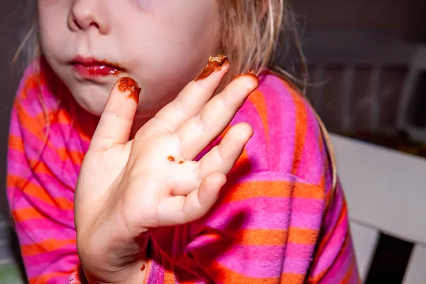 Маленька дівчинка їсть шоколадний бар Snickers на сніданок — стокове фото