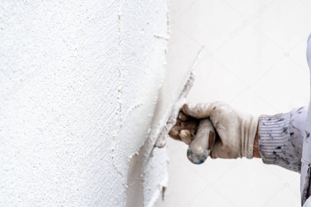 Construction worker plastering and smoothing concrete wall with cement