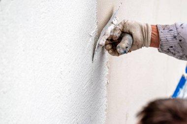 Construction worker plastering and smoothing concrete wall with cement clipart
