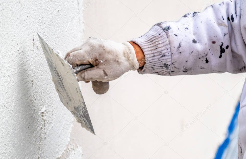 Construction worker plastering and smoothing concrete wall with cement