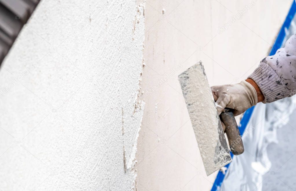 Construction worker plastering and smoothing concrete wall with cement