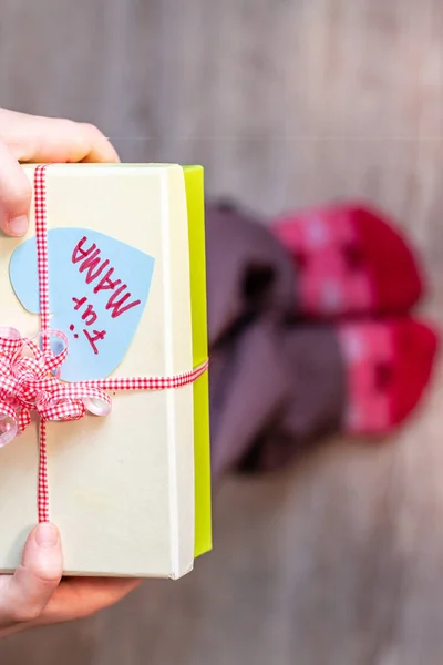 Little child holding gift box with ribbon and heart for her mum - Translation: for mum — Stock Photo, Image