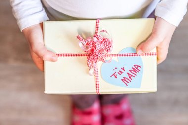 Küçük çocuk anne için şerit ve kalp ile hediye kutusu tutan-çeviri: anne için