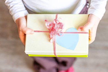 Küçük çocuk şerit ve kalp ile hediye kutusu tutarak