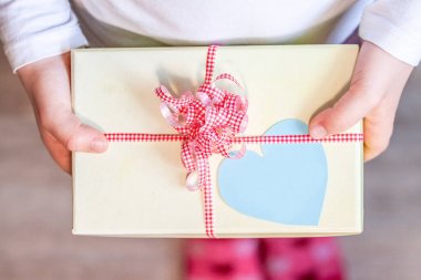 Küçük çocuk şerit ve kalp ile hediye kutusu tutarak