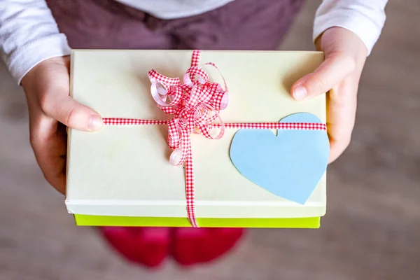 Little child holding gift box with ribbon and heart — Stock Photo, Image