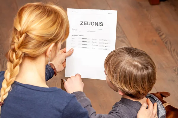 Mother comforting son despite the bad school certificate - Translation: certificate day of birth disciplines music reading religion german english mathematics art maths insufficient grade f deficient