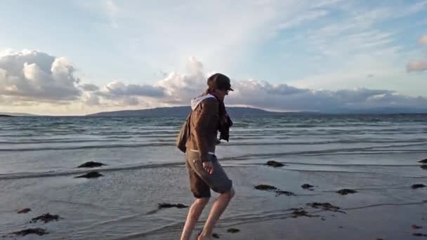 Dame loopt naar beneden het strand tijdens zonsondergang — Stockvideo