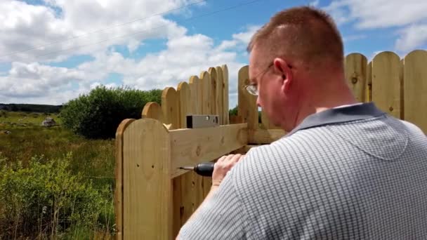 Drilling a screw into the wooden fence — Stock Video
