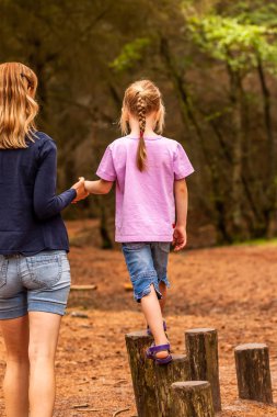 Anne tırmanma ve merdivene asılı ile oyun alanında kızı destekleyen