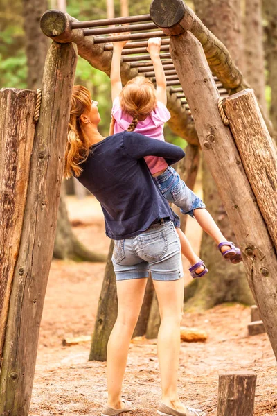 Anya támogatása lánya a játszótéren a hegymászás és lóg a létrán — Stock Fotó