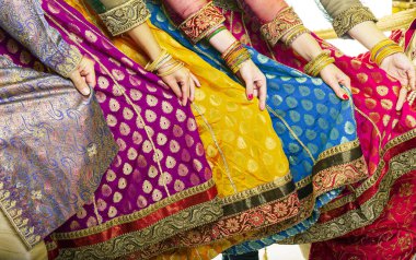 Bollywood dansçıları canlı kostümlerini tutuyorlar. Eller peş peşe