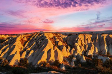 Türkiye 'nin Kapadokya kentinin yukarısından görülen sabah ışığı ile şekillenen kaya oluşumlarının canlı gündoğumu