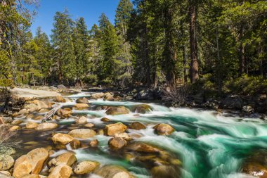 Yosemite Ulusal Parkı 'nda turkuaz suyu ve çok sayıda kaya bulunan Wild Merced nehri. Uzun pozlama. Kaliforniya, ABD
