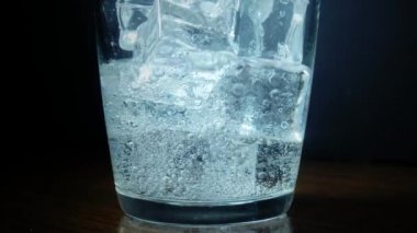 Yakın çekim buz küpleri ile gazlı su dökme