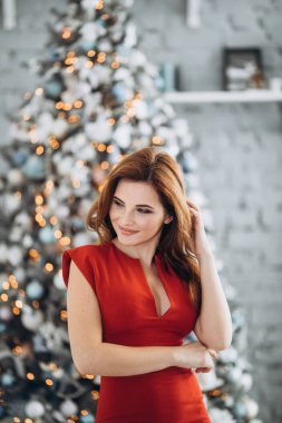 Noel. Noel ağacı kırmızı elbiseli güzel gülümseyen kadın Elegant arka plan ışıklar. Yeni Yılınız Kutlu Olsun.