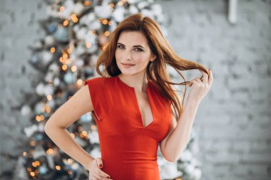 Noel. Noel ağacı kırmızı elbiseli güzel gülümseyen kadın Elegant arka plan ışıklar. Yeni Yılınız Kutlu Olsun.