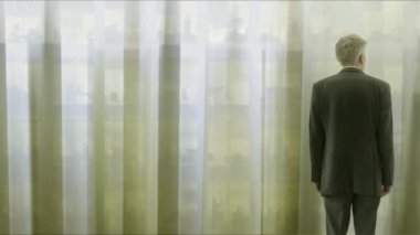 Arkadan Görünüş beyaz işadamı tefekkür beyaz perdelerin arasından bir pencereden dışarı bakıyor