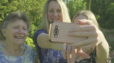Büyükanne, kızı ve büyük kızı bir selfie dışında bir smartphone bahçede taking