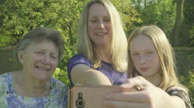 Büyükanne, kızı ve büyük kızı bir selfie dışında bir smartphone bahçede taking