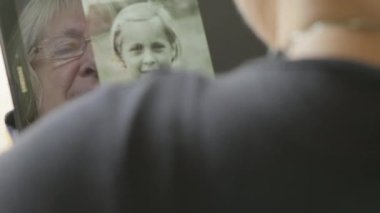 Üst düzey bir beyaz kadın kendini bir tablet bilgisayarda eski fotoğrafları bakarak yansıması 