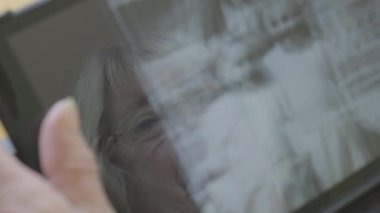 Beyaz kadın kendini bir tablet bilgisayarda eski fotoğrafları bakarak kıdemli 
