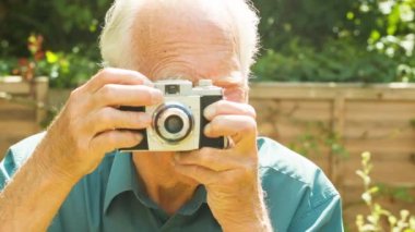 Bir aktif kıdemli beyaz portre onun bahçesinde eski bir film kamera ile alarak fotoğraf dostum