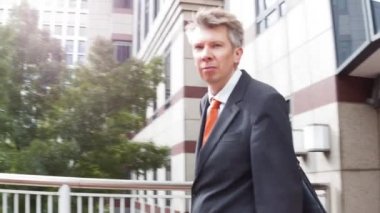 Akıllı orta yaşlı beyaz işadamı bürosundan çıkarken kalabalık saatte yürüyüş