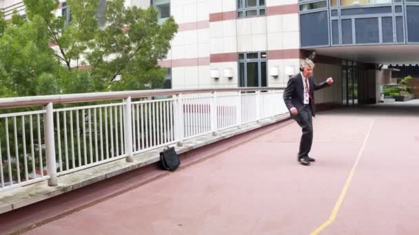 Happy Carefree Caucasian Businessman Leaving Office Wearing Headphones Listening Music — Stockvideo