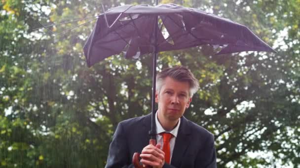 白种商人躲在雨中一把破碎的雨伞下面 — 图库视频影像