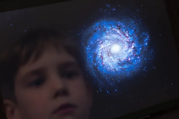 Reflection of a young boy looking at a galaxy on a tablet computer themes of science discovery awe  - Created with a Public Domain image from NASA