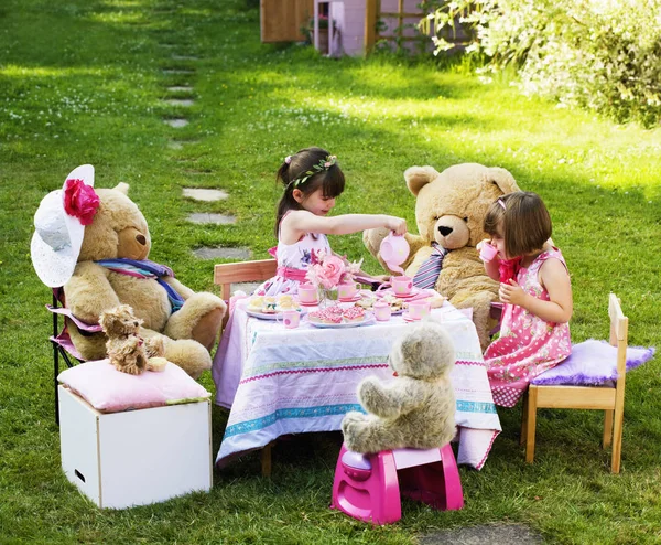 Dwie młode dziewczyny grają Teddy Bears piknik w ich tylnym ogrodzie — Zdjęcie stockowe
