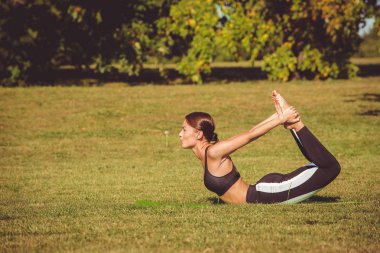 kadın parkta pratik yoga, Dhanurasana poz
