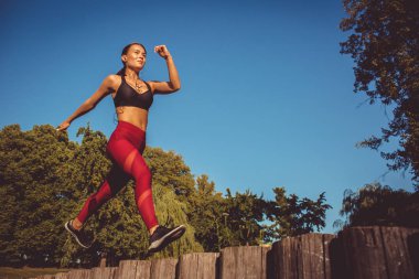 kadın kırmızı tozluk ve koşma ve atlama park, düşük açılı görünüş sportif üst